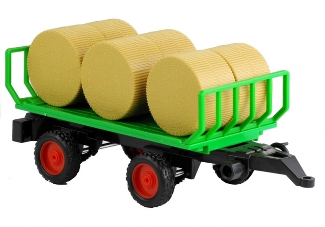 Tractor verde cu remorcă și baloturi de fân
